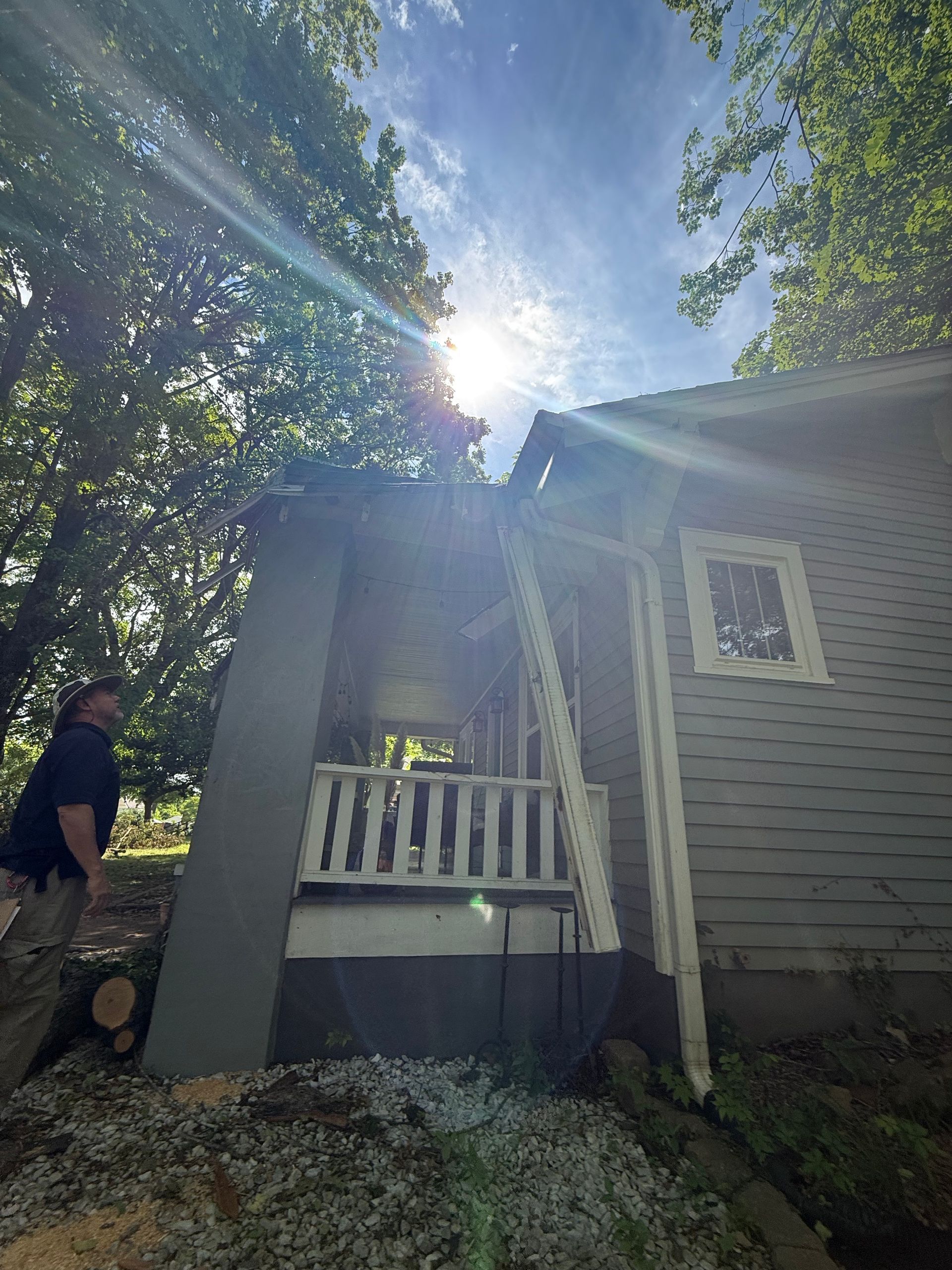 A man is standing in front of a house with a ladder.