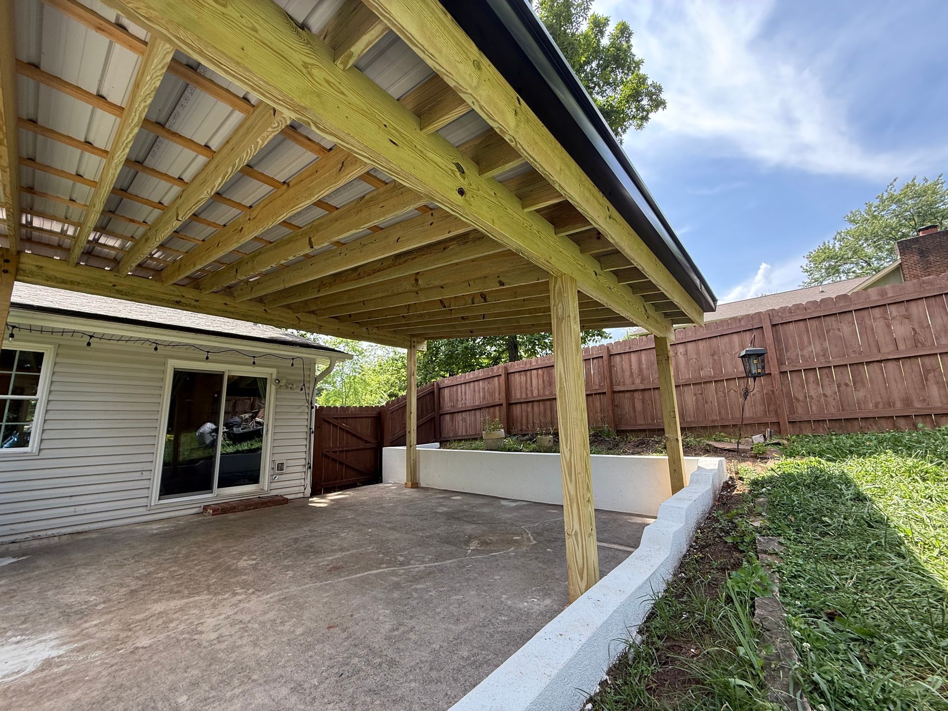A wooden covered area in the backyard of a house.