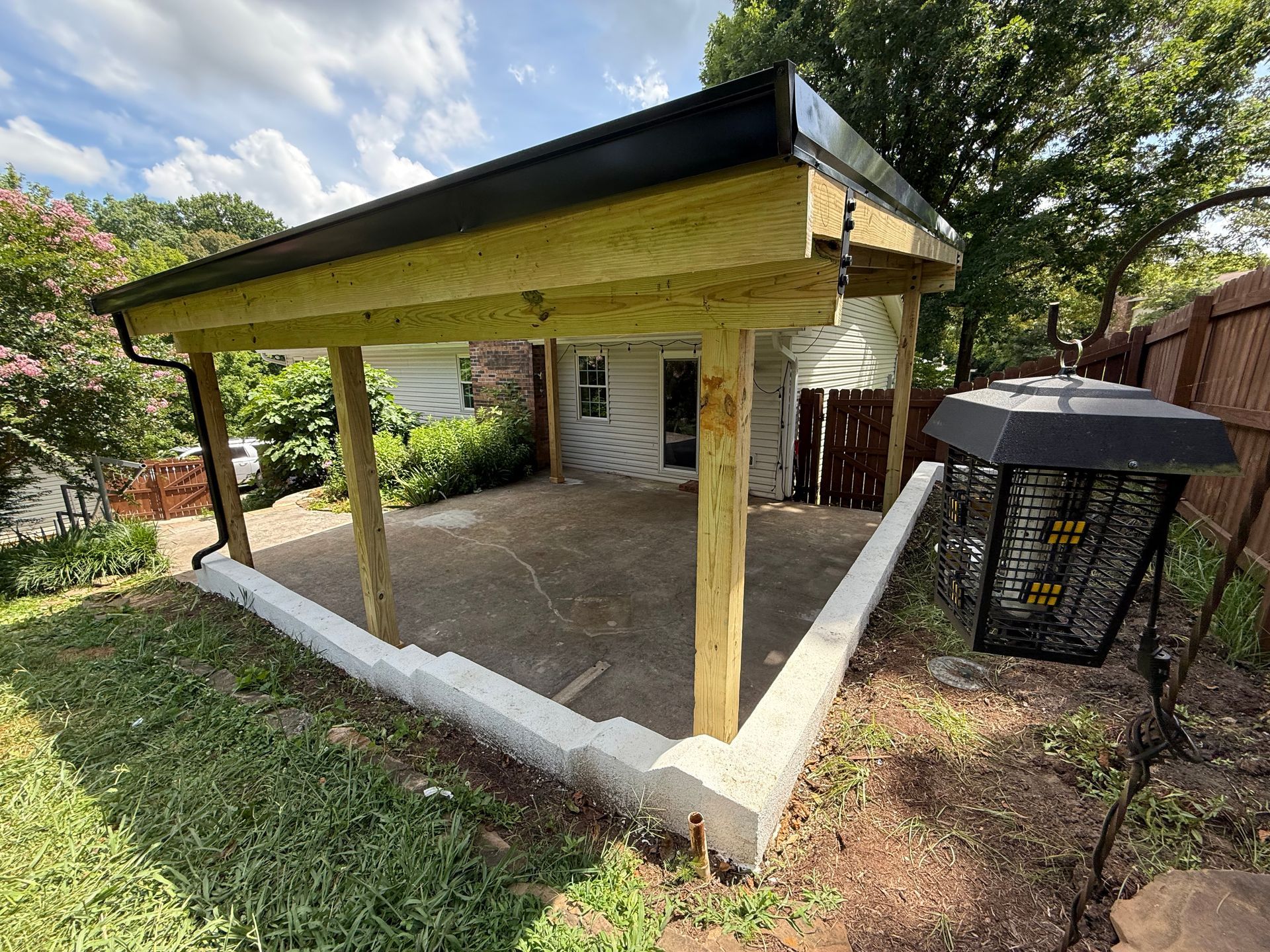 A carport is being built in the backyard of a house.