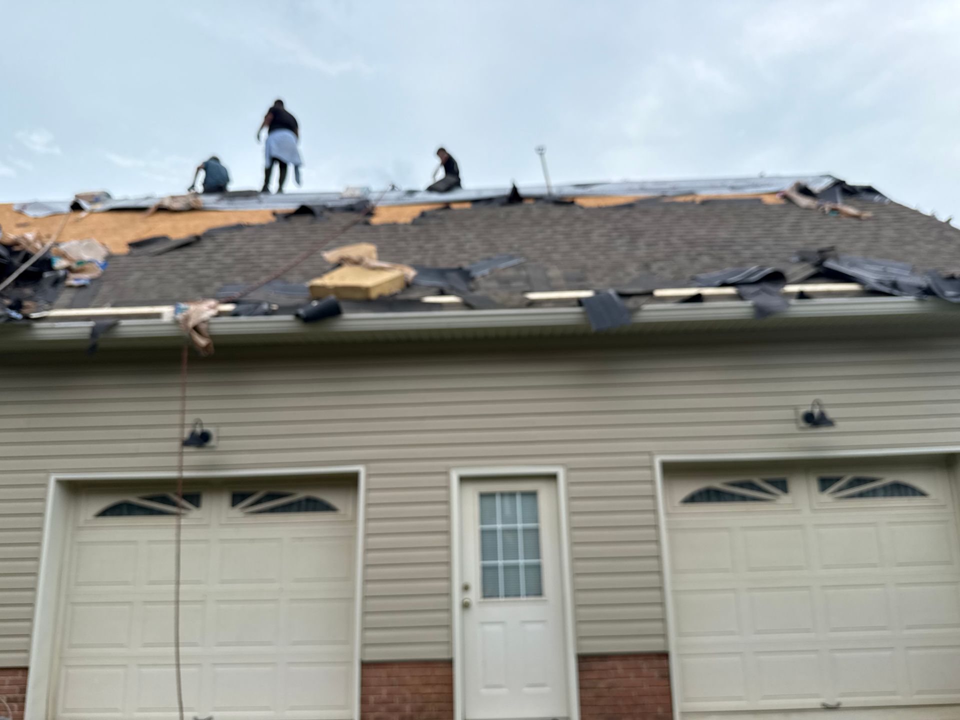 Two men are working on the roof of a house.