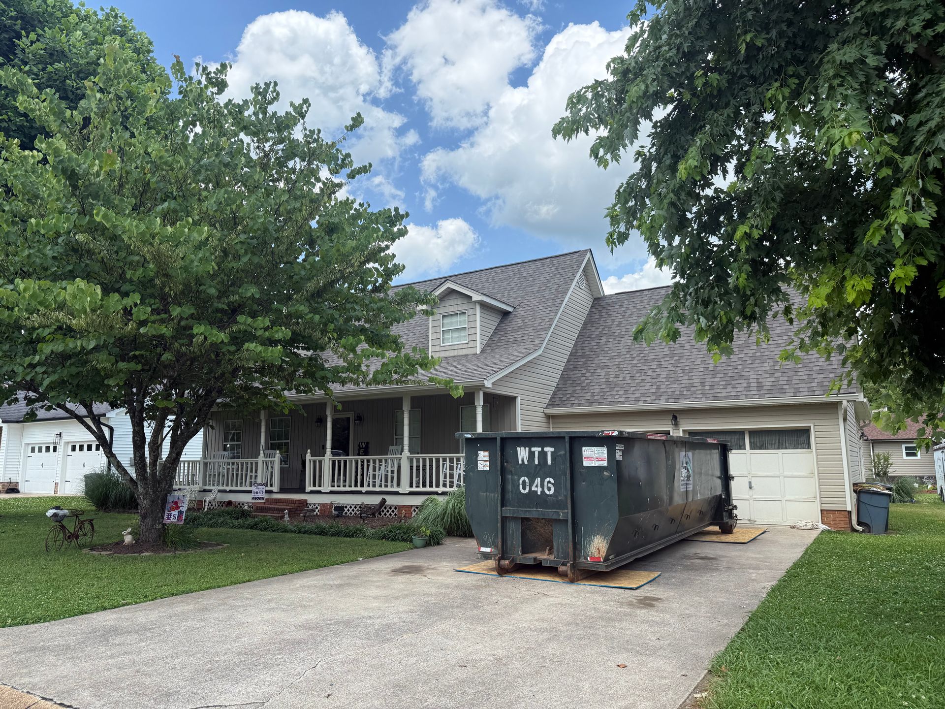 A large dumpster is parked in front of a house.