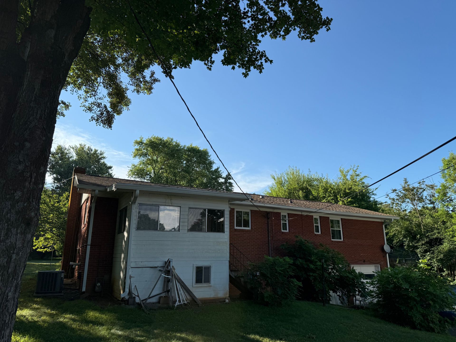 A house with a tree in front of it and a blue sky