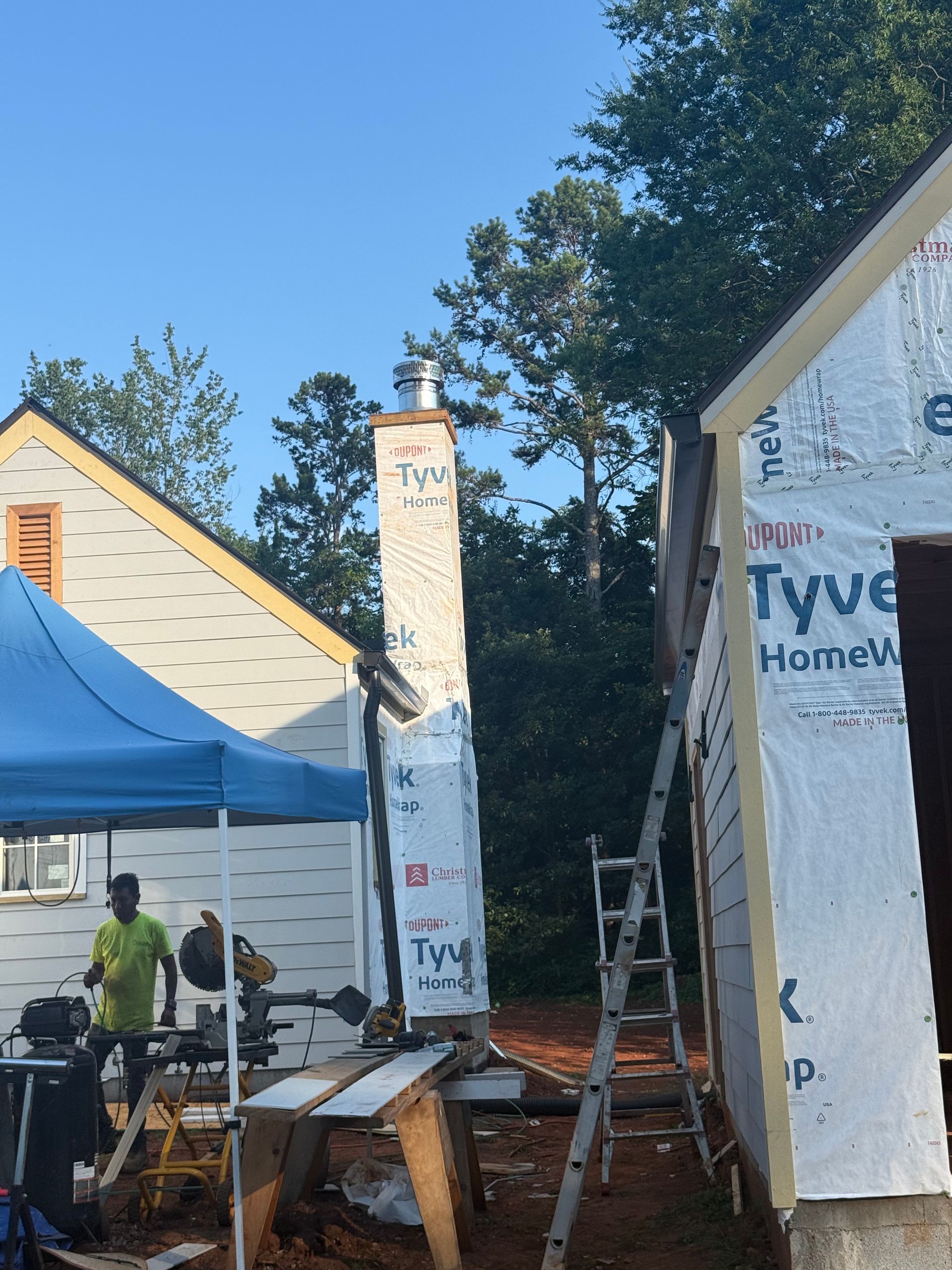A blue tent is in front of a building that says tyve home