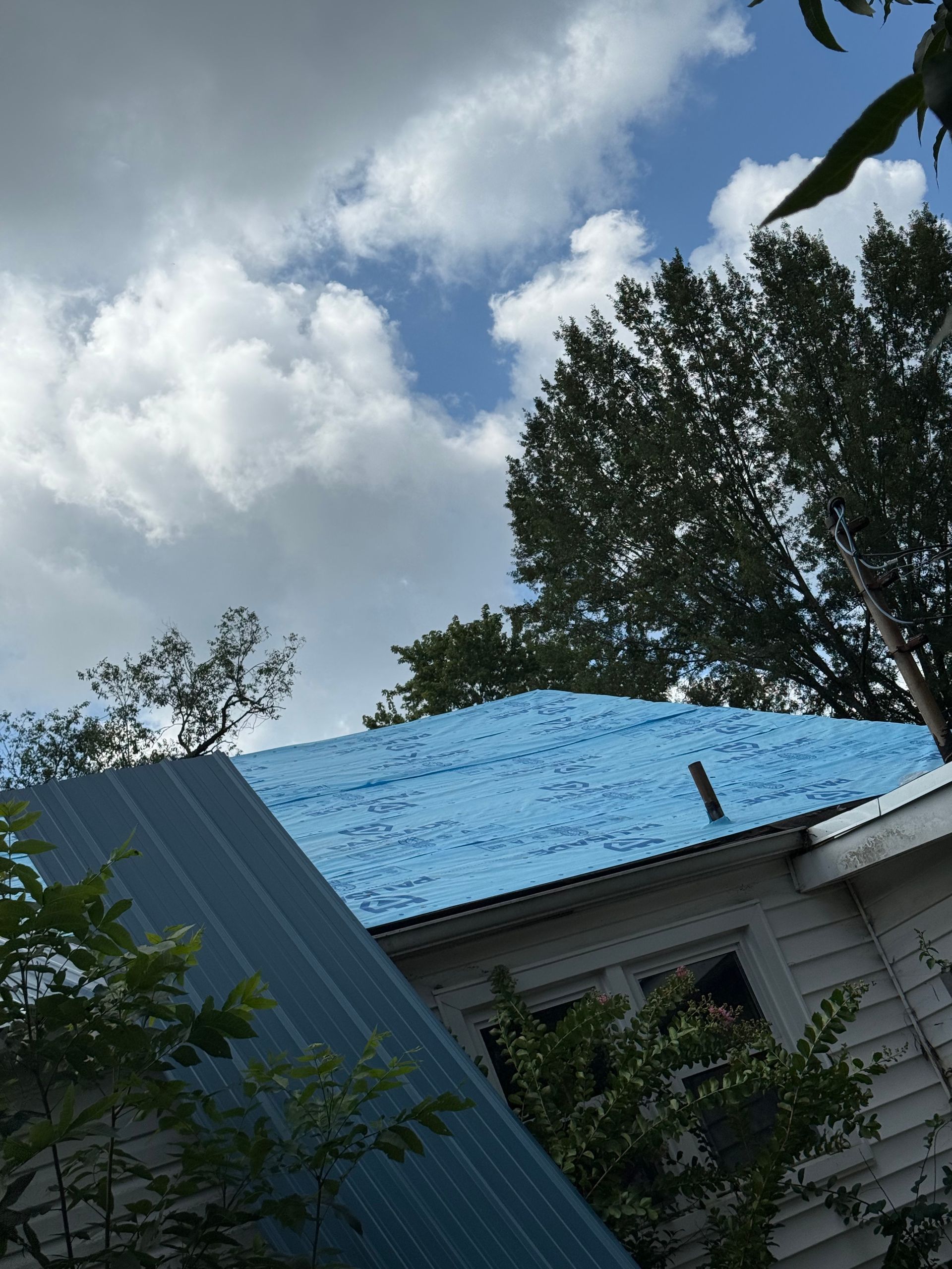 A blue tarp is covering the roof of a house.