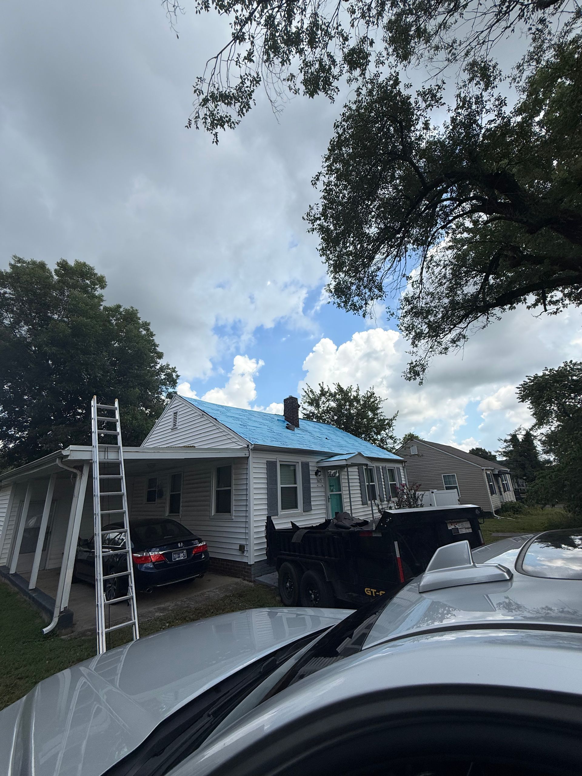 A car is parked in front of a house with a blue roof.