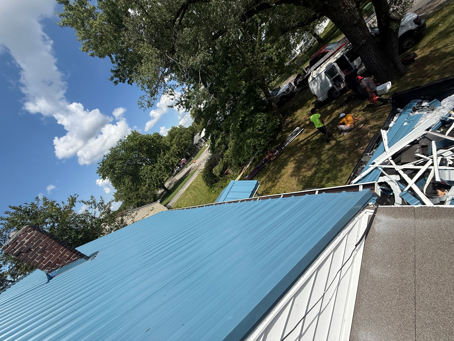 A blue metal roof is being installed on a house.