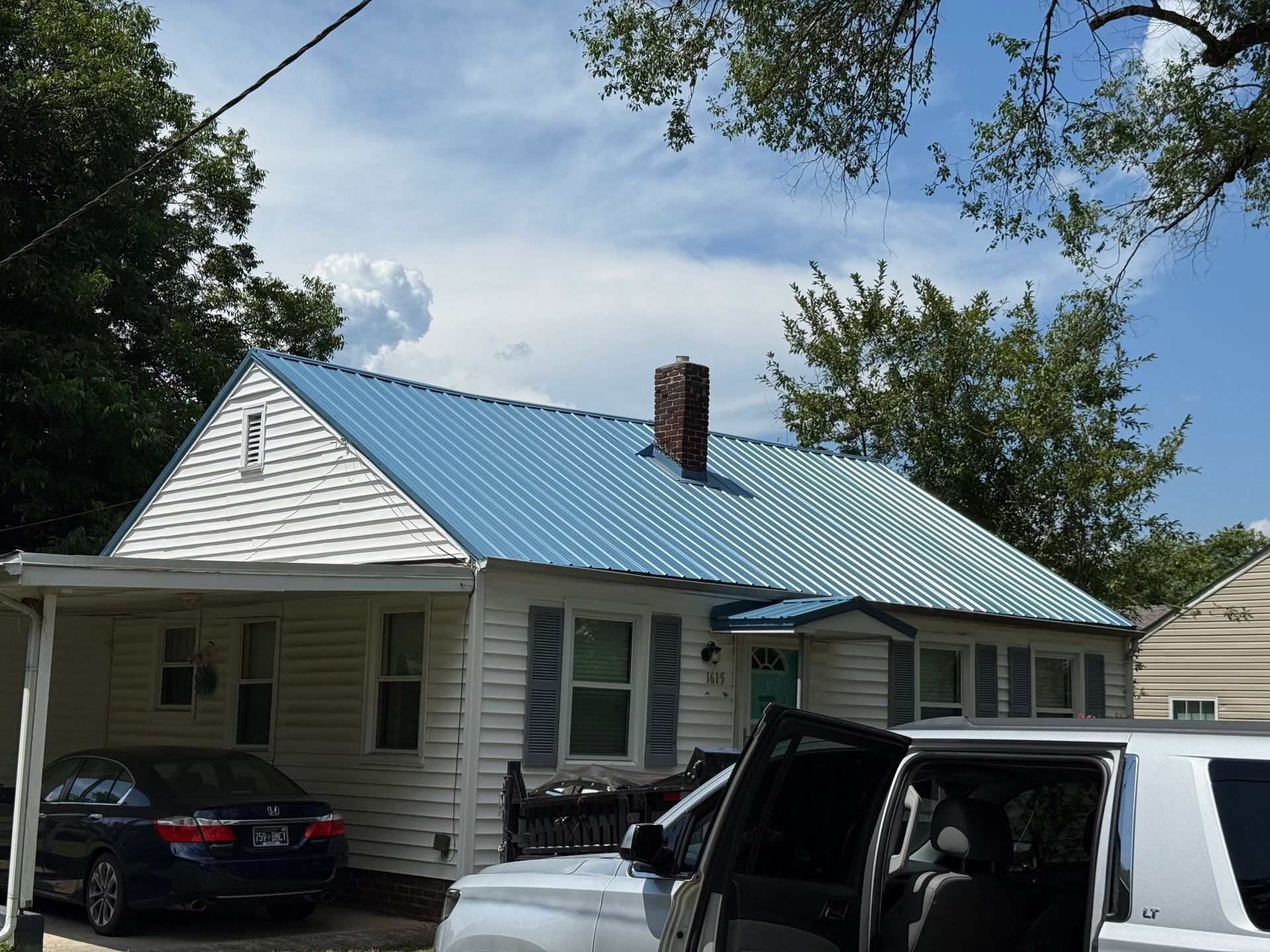A white house with a blue roof and a white truck parked in front of it
