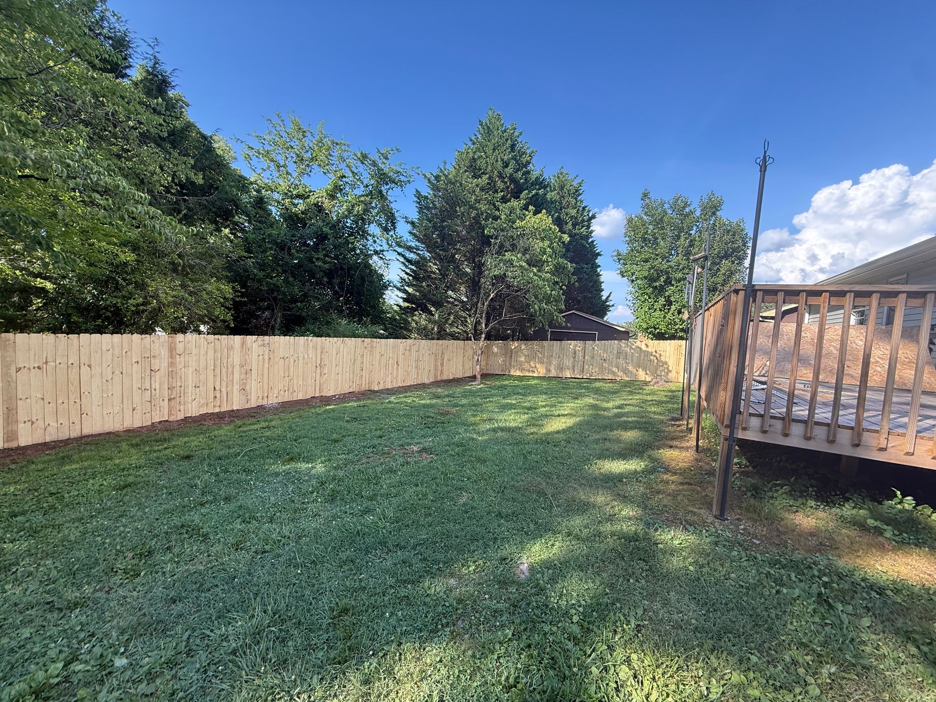 A backyard with a wooden fence and a deck.
