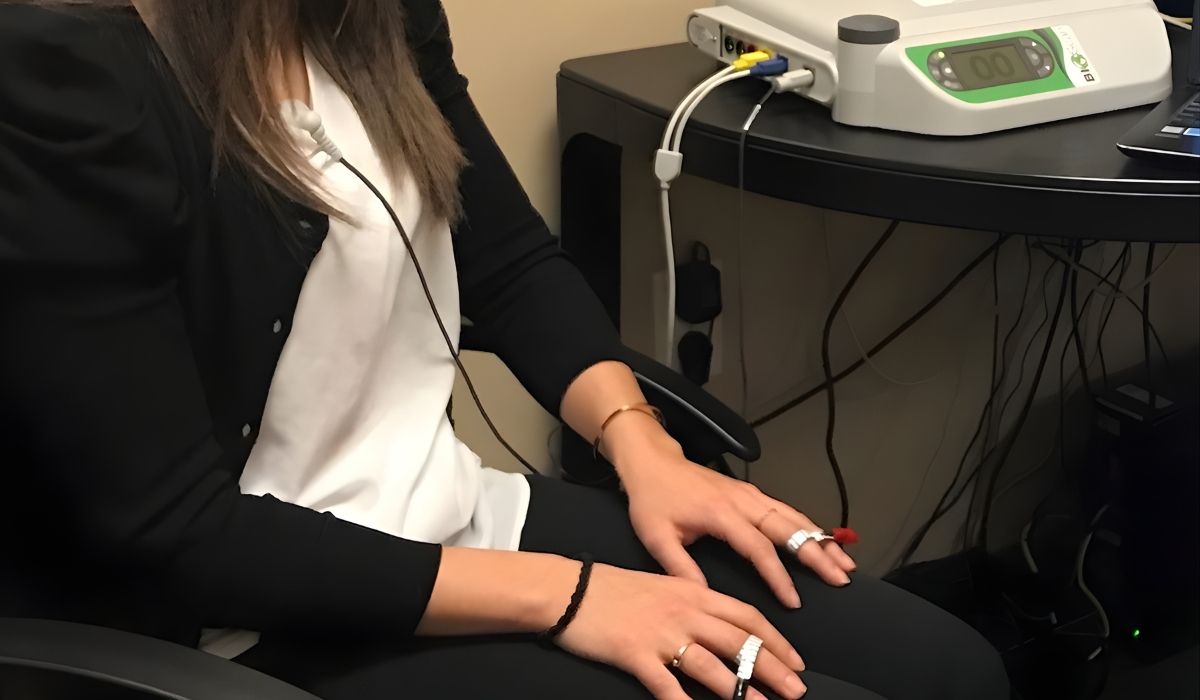 Person seated beside a table connected to a Bioscan device, hands resting on their lap