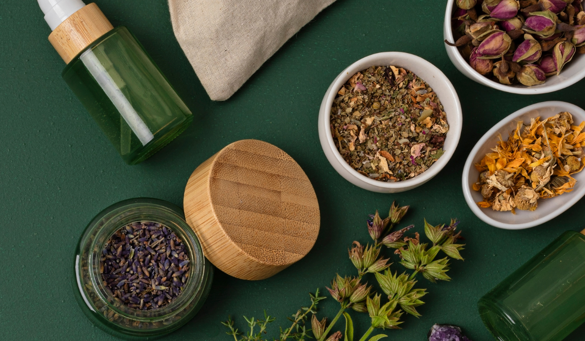 Herbal tea ingredients in bowls and jars on a dark green background