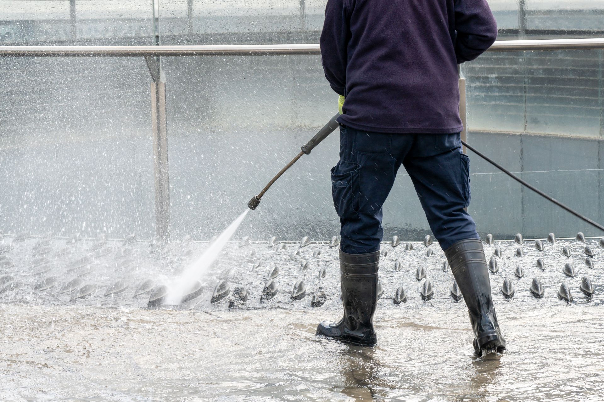 A worker is providing a commercial pressure washing service to clean a public walkway and fountain. A worker is providing a commercial pressure washing service to clean a public walkway and fountain.