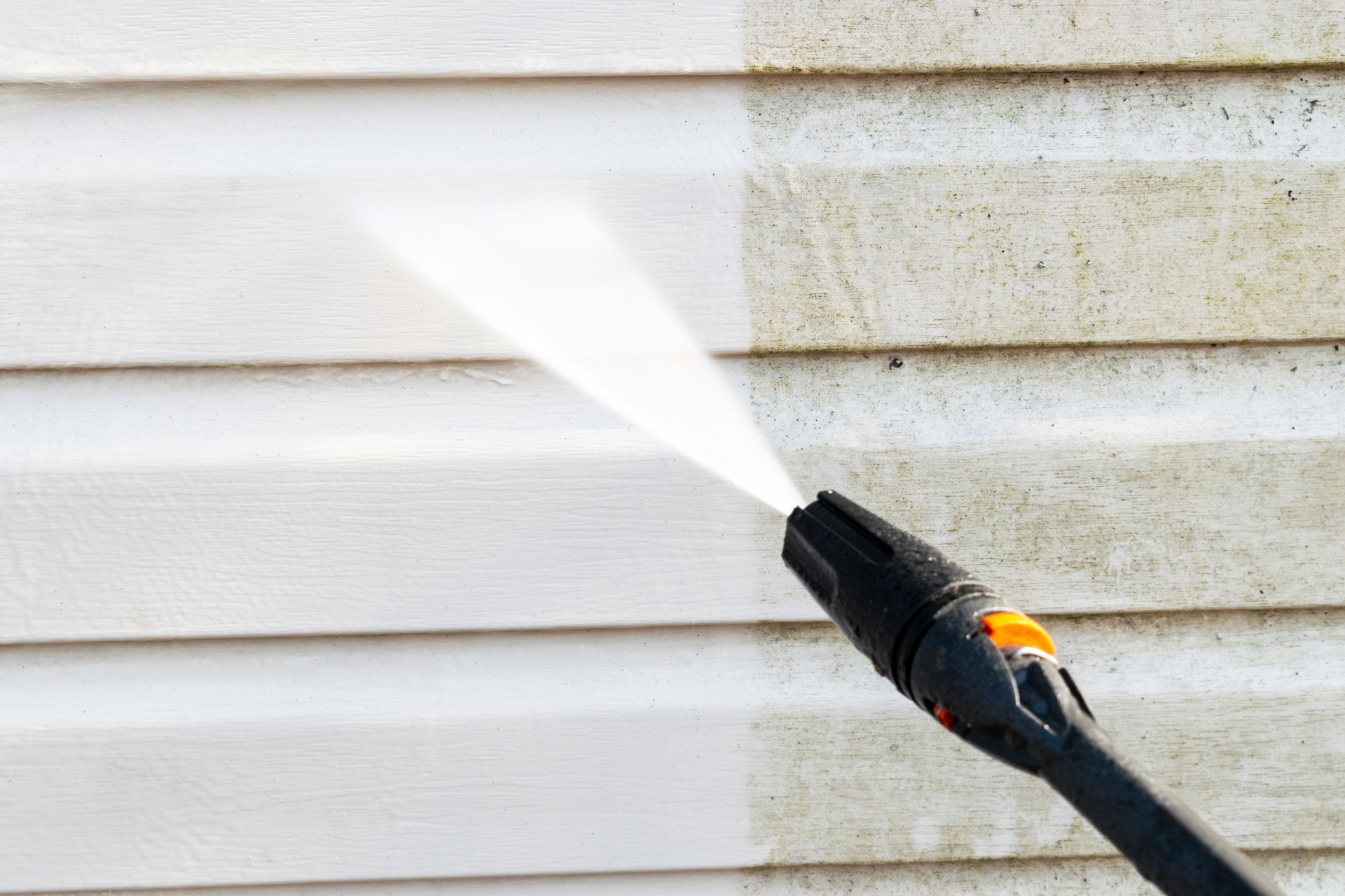 Professional pressure washing service removing mold and grime from residential vinyl siding.