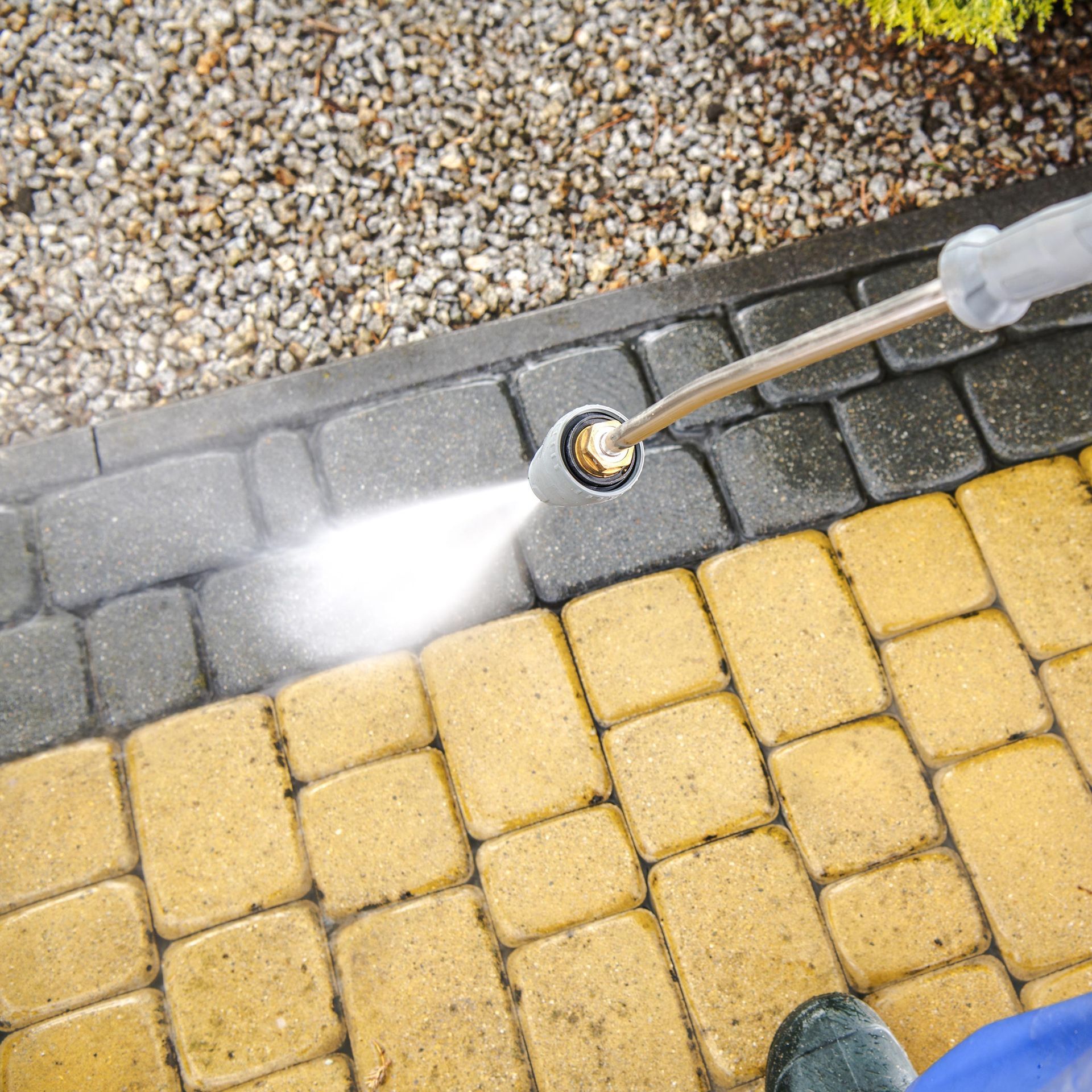 Close-up of a worker performing a pressure washing service on a driveway's bricks. Close-up of a worker performing a pressure washing service on a driveway's bricks.