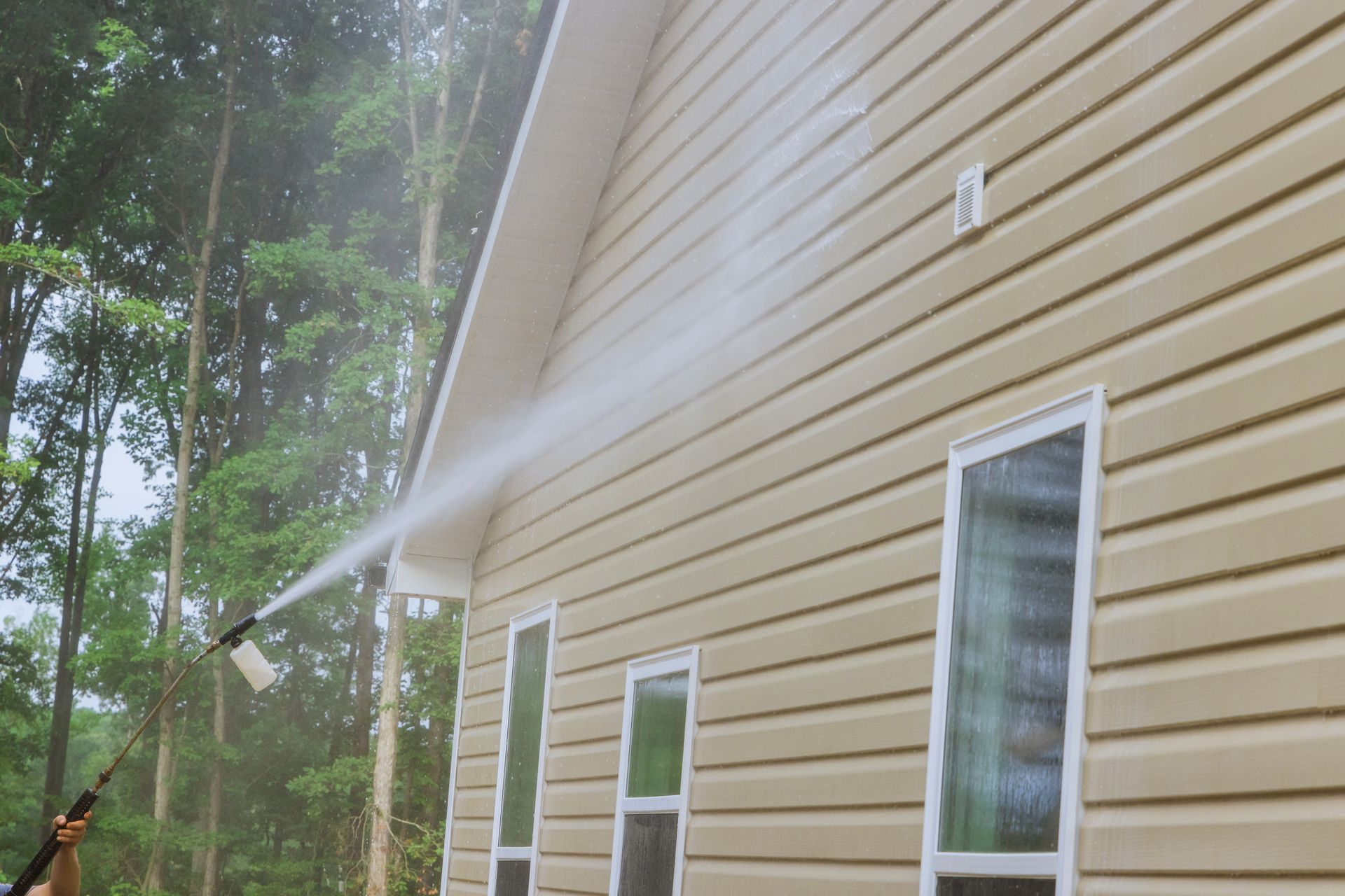 A pressure washer is being used to clean a house.