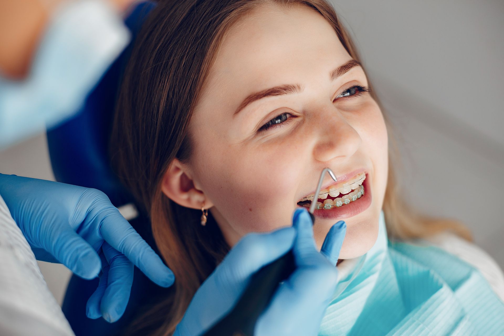 Odontologia en Moma Clinic Andorra. Una mujer está sentada en un sillón dental mientras un dentista examina sus dientes.