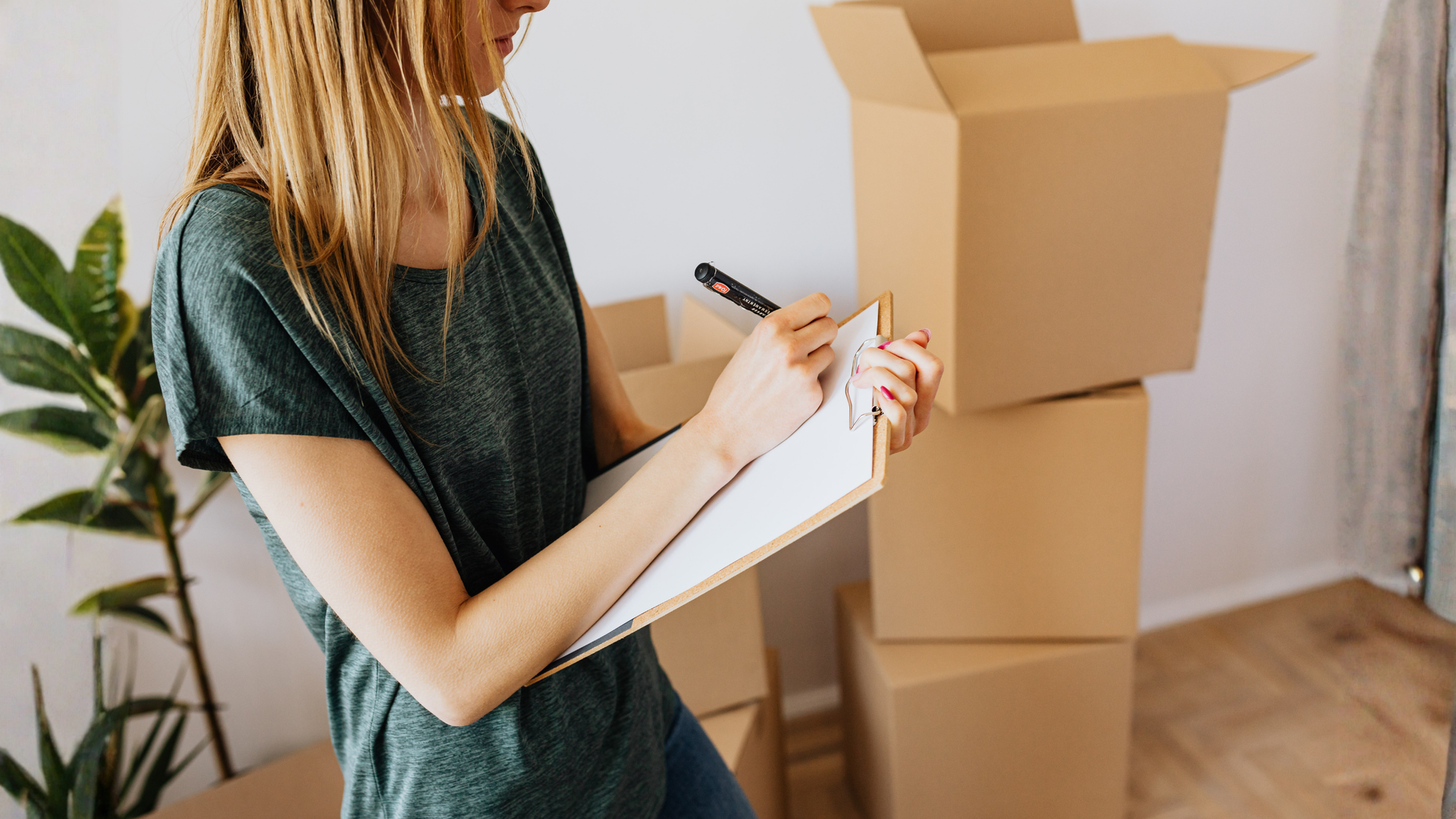 Person completing a maintenance checklist on a clipboard near stacked cardboard boxes. Person completing a maintenance checklist on a clipboard near stacked cardboard boxes.