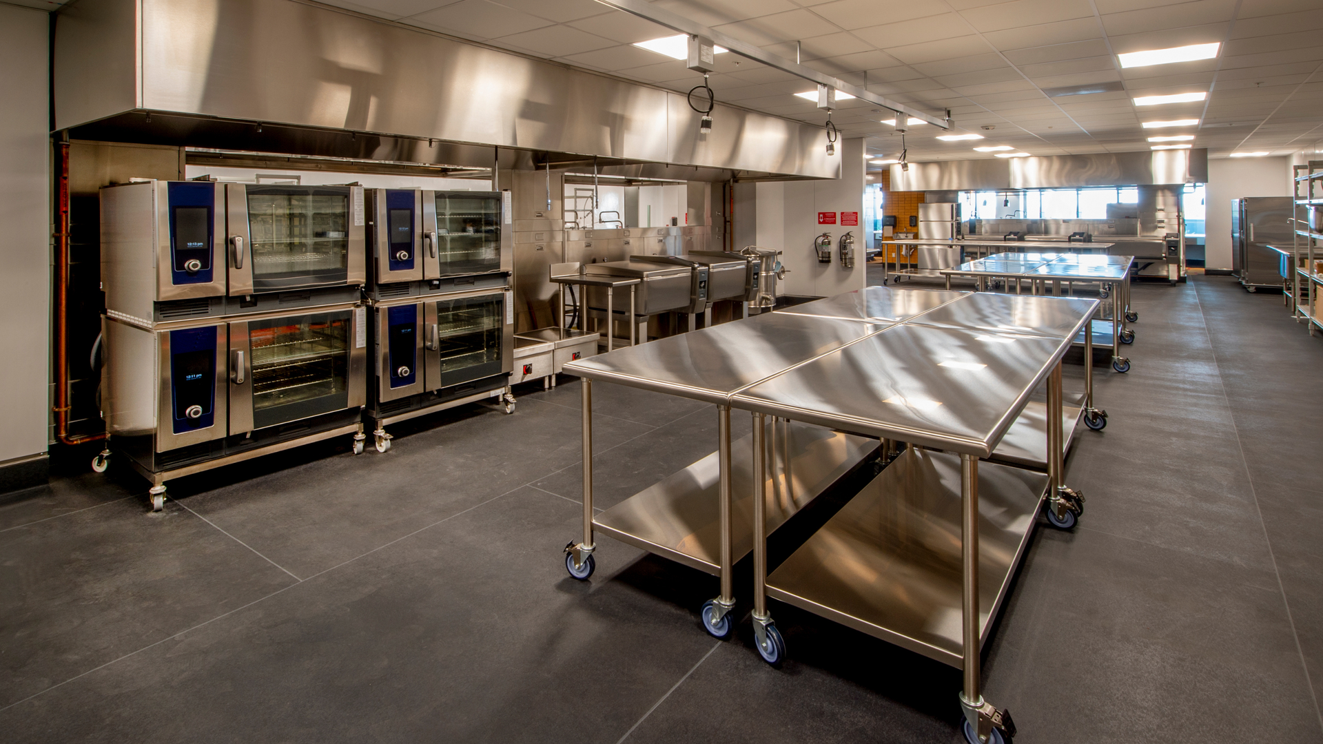 Stainless steel commercial kitchen fit out with prep benches and ventilation canopy.