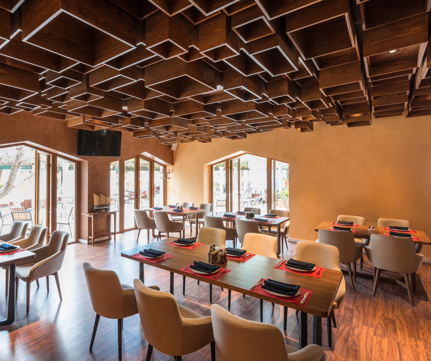 Modern restaurant dining room with wood lattice ceiling, tables, and chairs by large windows