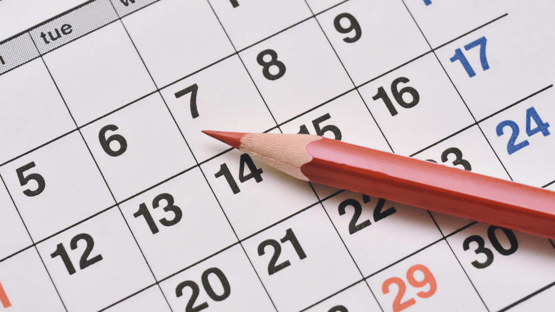 Close-up of a calendar page with a red pencil pointing at dates. Close-up of a calendar page with a red pencil pointing at dates.
