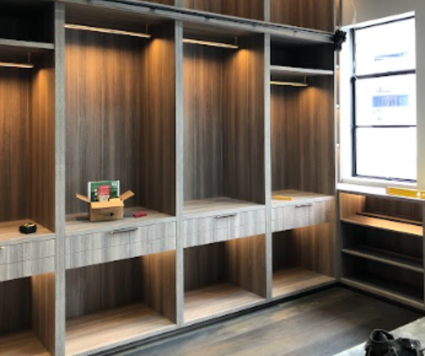 Built-in wooden cubby shelves with drawers in a modern room beside a bright window. Built-in wooden cubby shelves with drawers in a modern room beside a bright window.