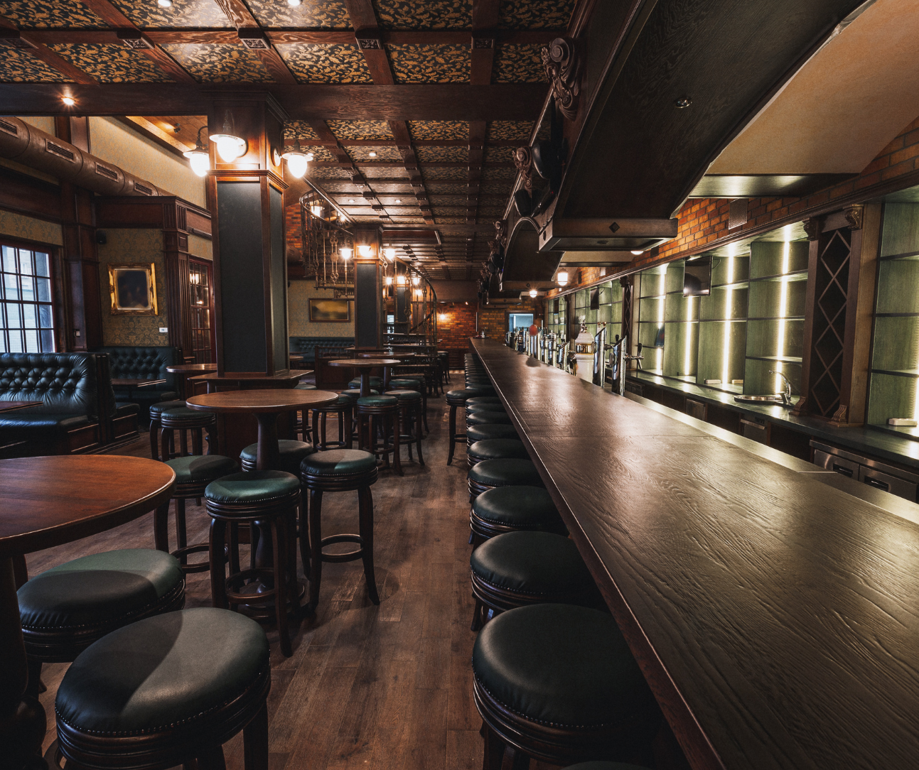 Empty dimly lit bar interior with long counter, stools, and warm industrial lighting Empty dimly lit bar interior with long counter, stools, and warm industrial lighting