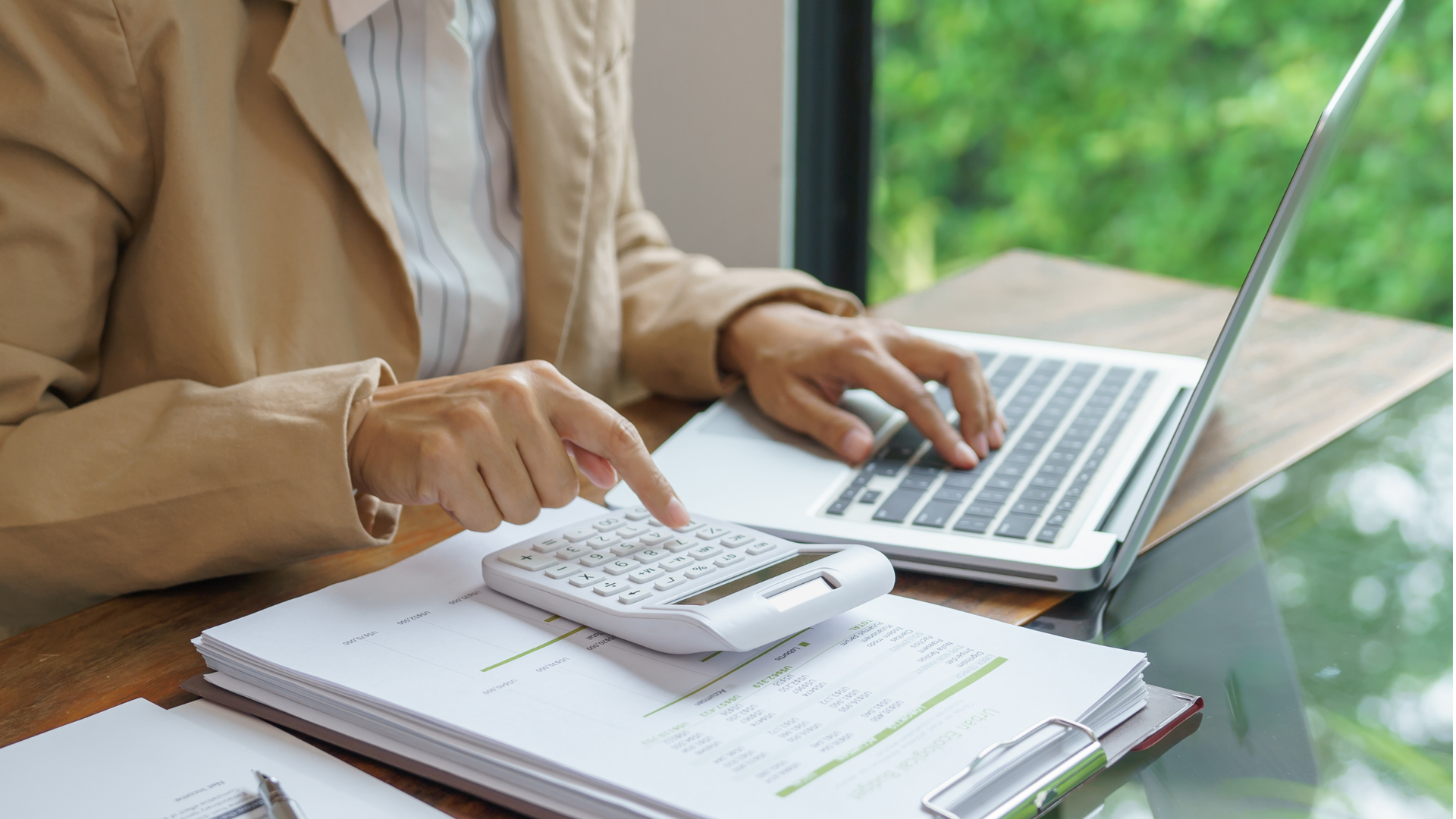 Person calculating commercial fit out budget with calculator and laptop.