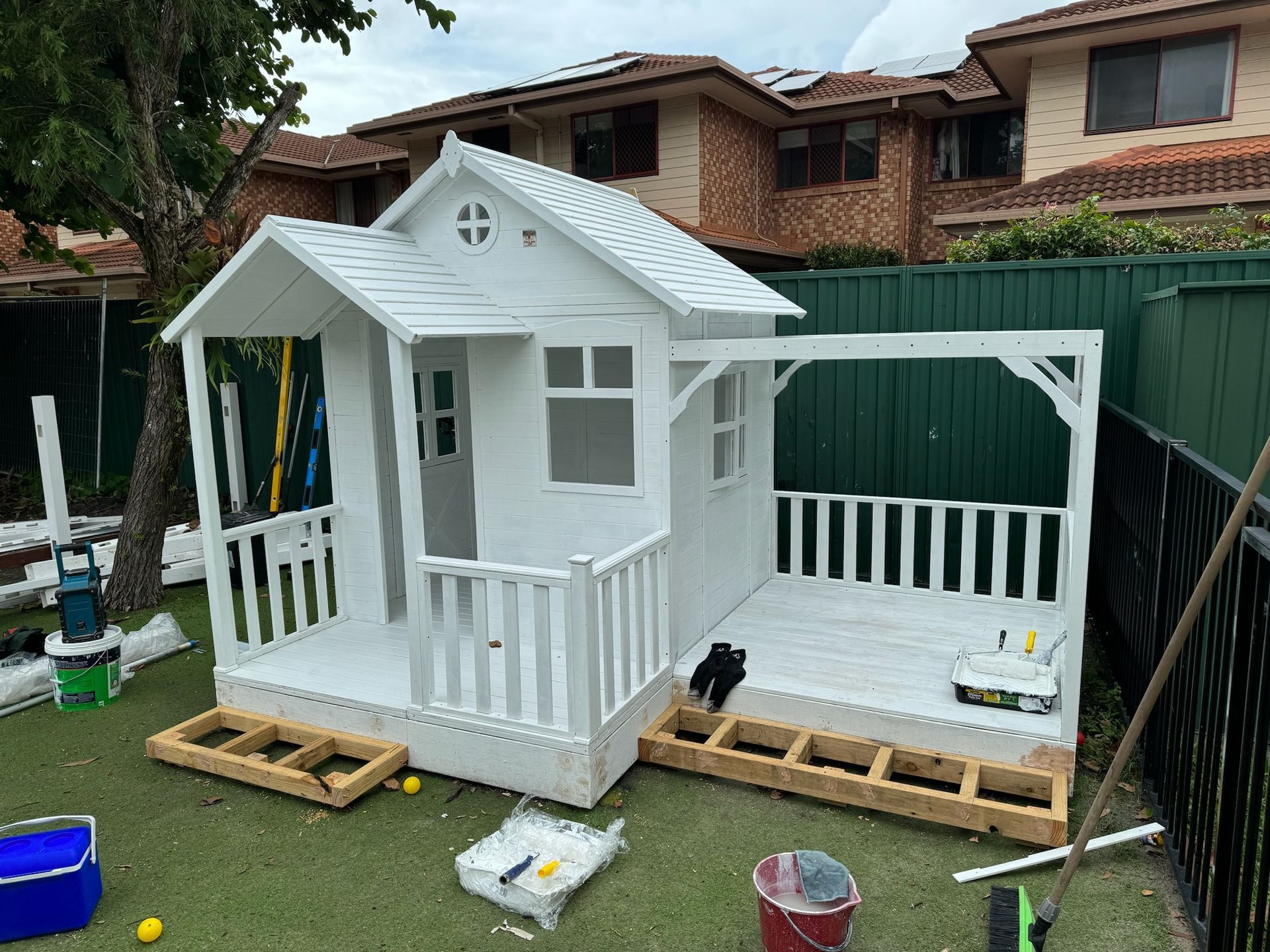 A white playhouse is being built in a backyard.