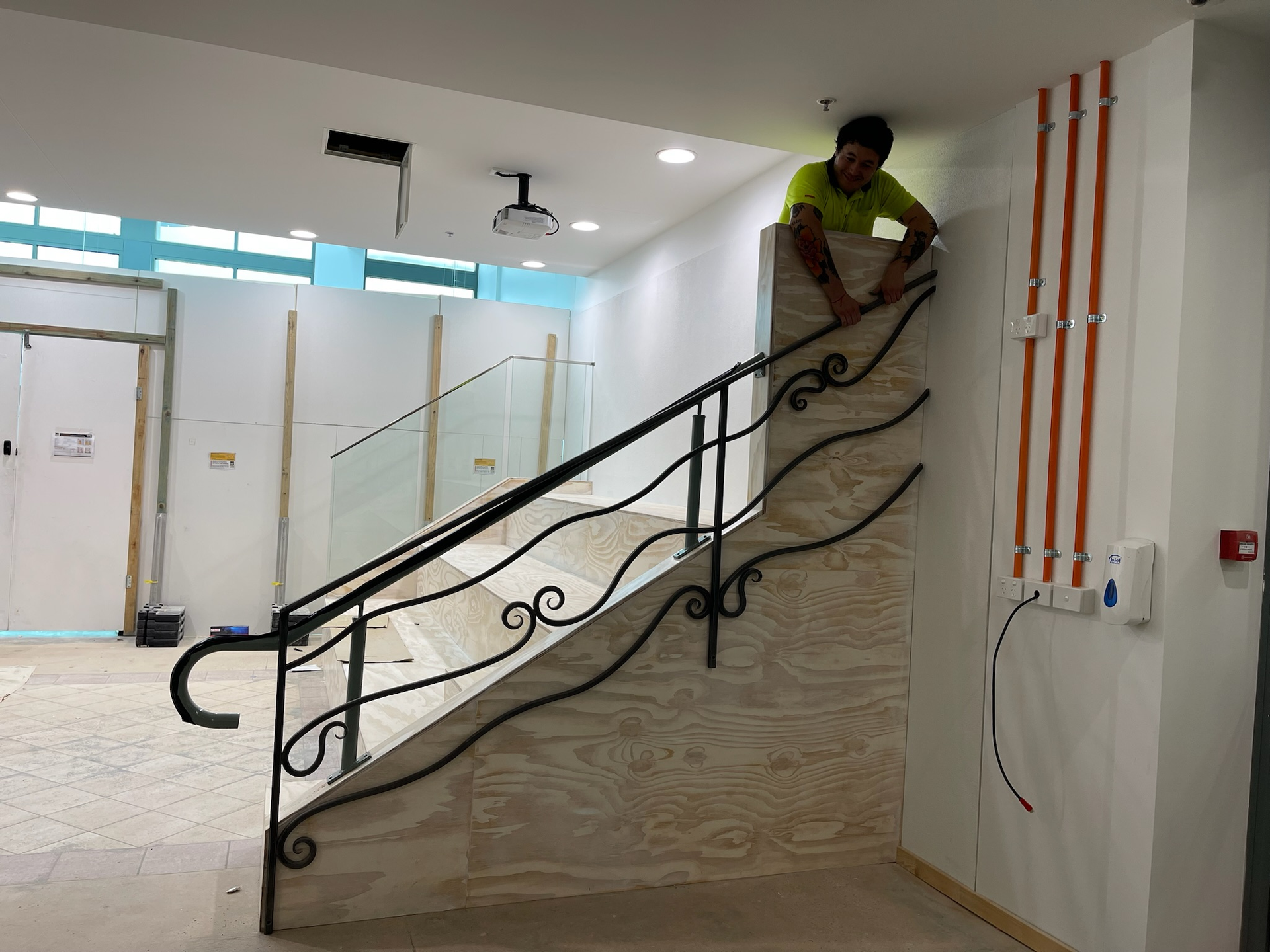 Commercial builder installing a decorative black handrail on an internal timber staircase during a Brisbane office fitout. Commercial builder installing a decorative black handrail on an internal timber staircase during a Brisbane office fitout.