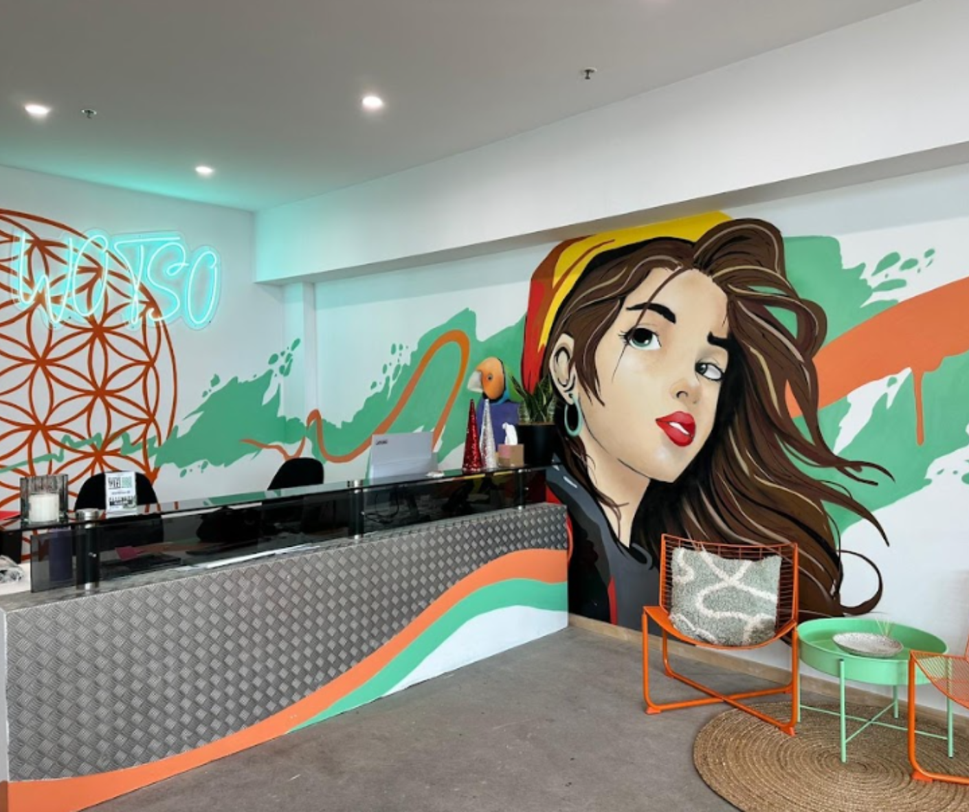 Modern café interior with a colorful mural, black counter, and orange-and-green seating Modern café interior with a colorful mural, black counter, and orange-and-green seating