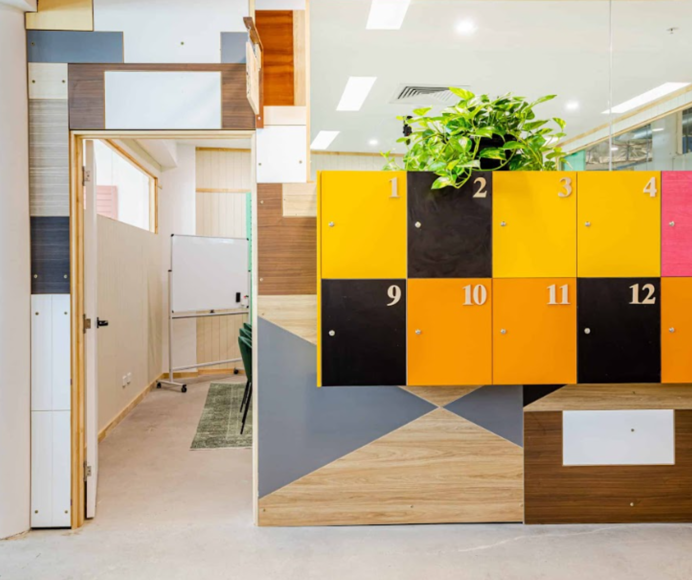 Office hallway with yellow-and-black lockers and a potted plant on top, beside wooden partitions. Office hallway with yellow-and-black lockers and a potted plant on top, beside wooden partitions.