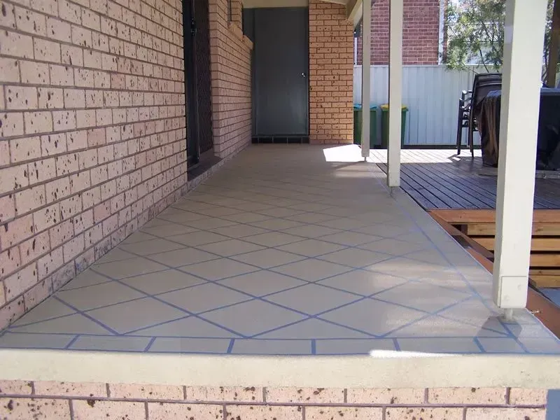 Covered Brick Porch With Tiled Floor, White Posts, and a Doorway at the End — Concrete Colour Solutions in Dungog, NSW