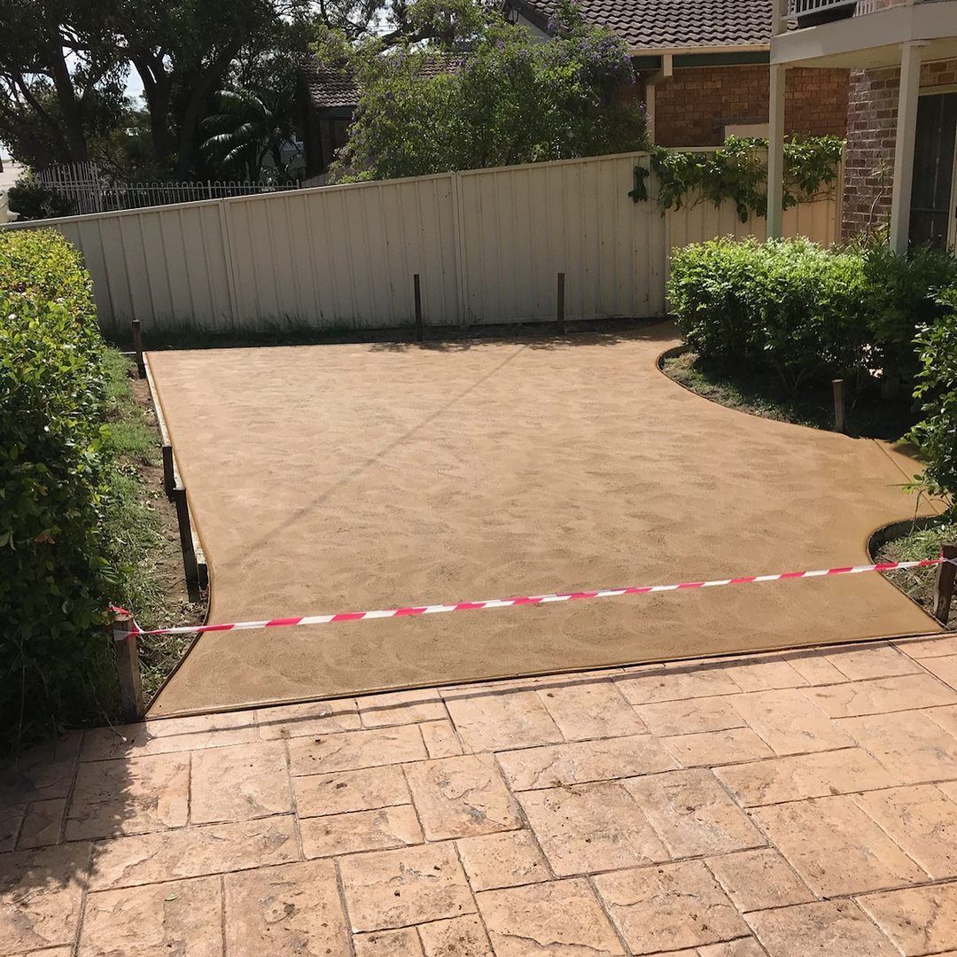 A Concrete Driveway with A White Fence in The Background — Concrete Colour Solutions in Nelson Bay, NSW