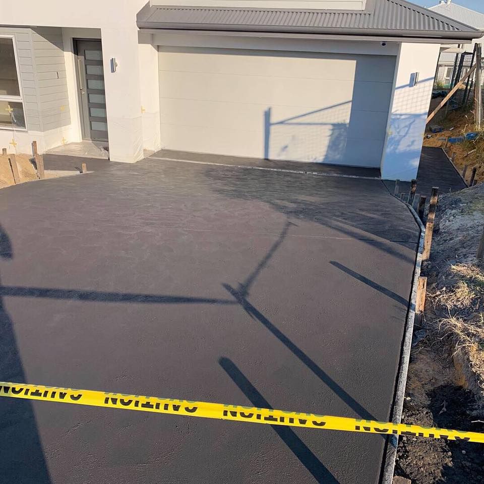 A Concrete Driveway Is Being Built in Front of A House — Concrete Colour Solutions in Morisset, NSW