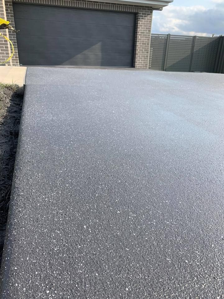 A Gray Concrete Driveway with A Garage Door in The Background — Concrete Colour Solutions in Port Stephens, NSW