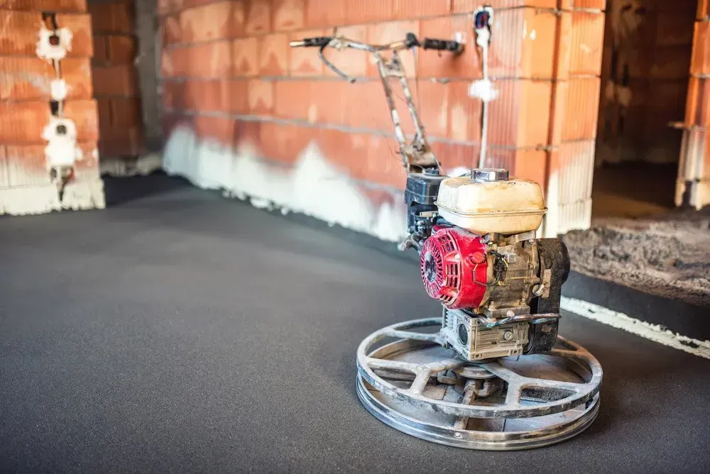 A Machine on The Floor in A Room with A Brick Wall in The Background — Concrete Colour Solutions in Central Coast, NSW