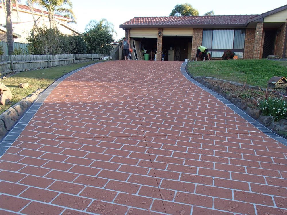 Brick-paved Driveway Curving Up to a House With a Garage — Concrete Colour Solutions in Muswellbrook, NSW