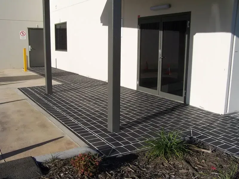 A white building with a black patio in front of it — Concrete Colour Solutions in Morisset, NSW
