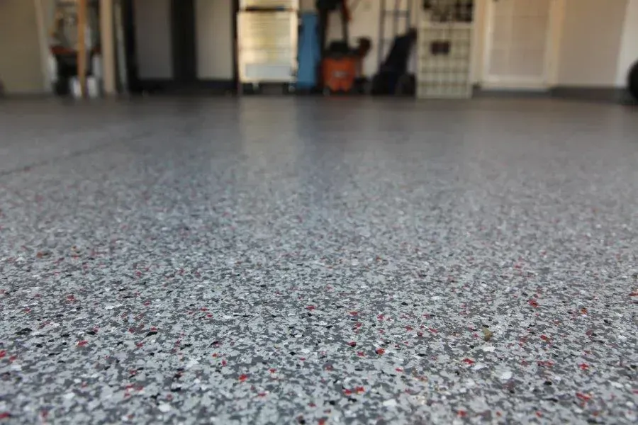 Speckled Gray Garage Floor With a Blurred Room in the Background — Concrete Colour Solutions in Singleton, NSW