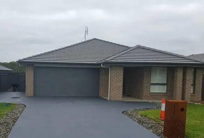 A brick house with a garage and a driveway in front of it. — Concrete Colour Solutions in Morisset, NSW