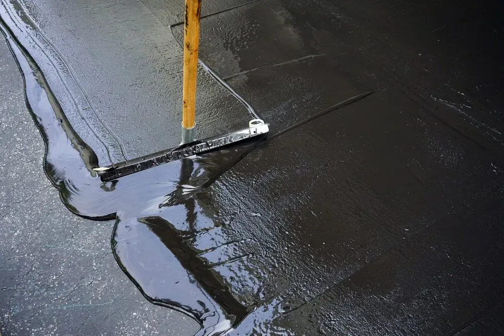 A Hose Is Spraying Water on A Black Concrete Surface — Concrete Colour Solutions in Cessnock, NSW