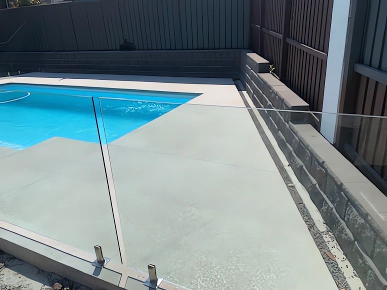 A Swimming Pool with A Glass Fence Around It — Concrete Colour Solutions in Heatherbrae, NSW