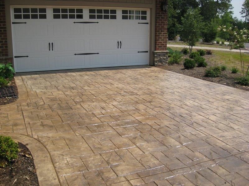 A driveway leading to a garage with a white door — Concrete Colour Solutions in Morisset, NSW