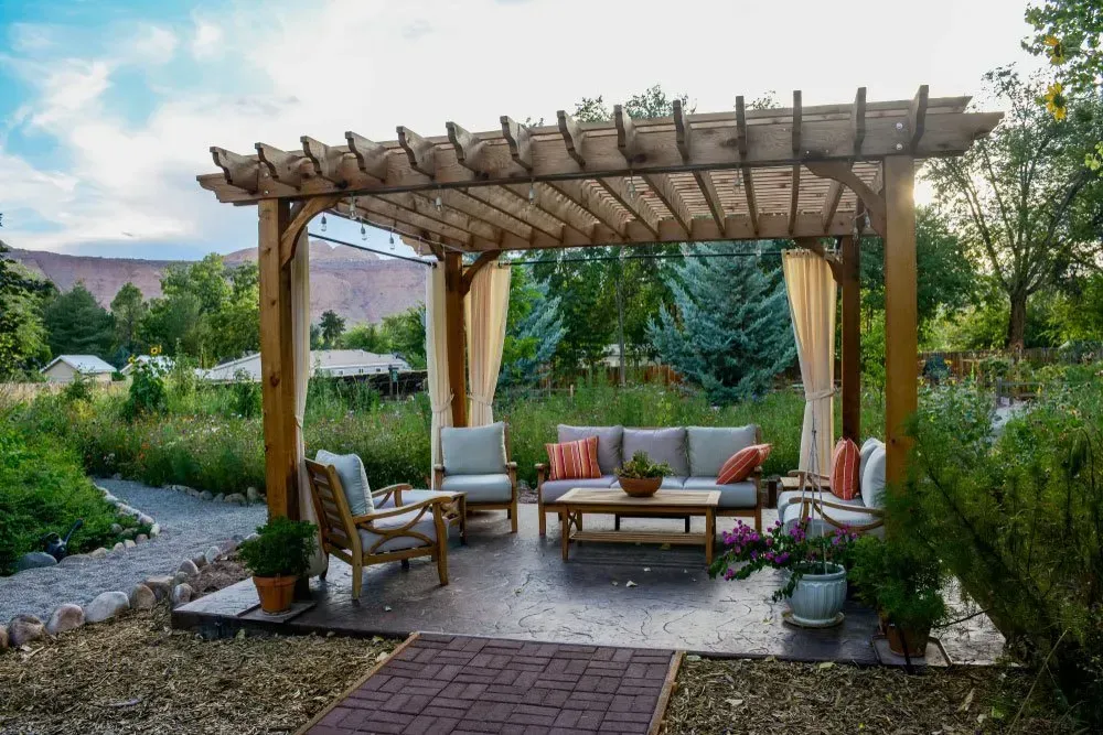 A Wooden Pergola with A Couch and Chairs Underneath It — Concrete Colour Solutions in Morisset, NSW
