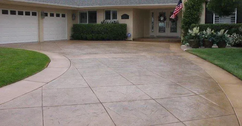 A Concrete Driveway Leading to A House with Two Garage Doors — Concrete Colour Solutions in Cessnock, NSW