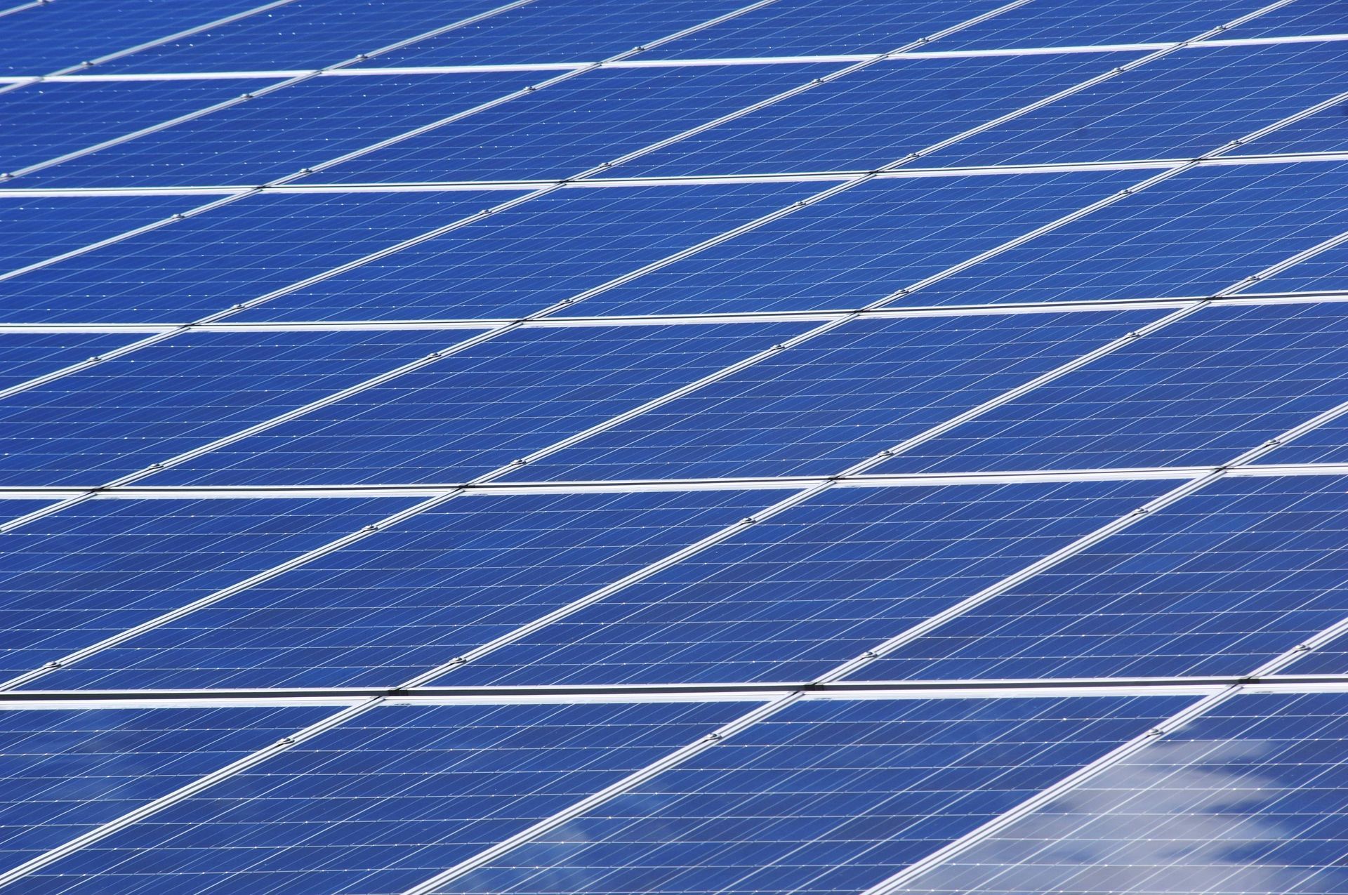Aerial view of blue solar panels in geometric rows at utility-scale renewable energy facility