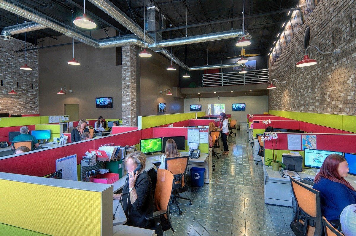 The image show an office setting with colorful open plan office cubicles. 