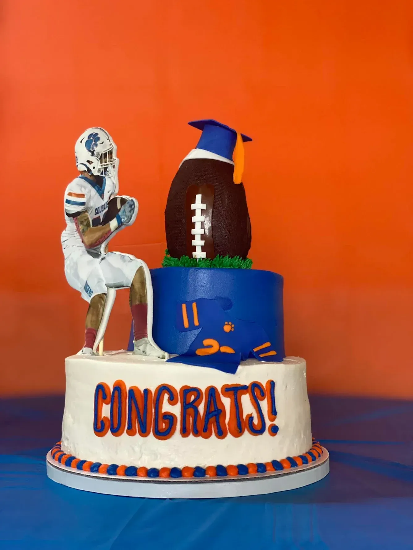 Graduation cake with football theme; player figurine, football with mortarboard, 