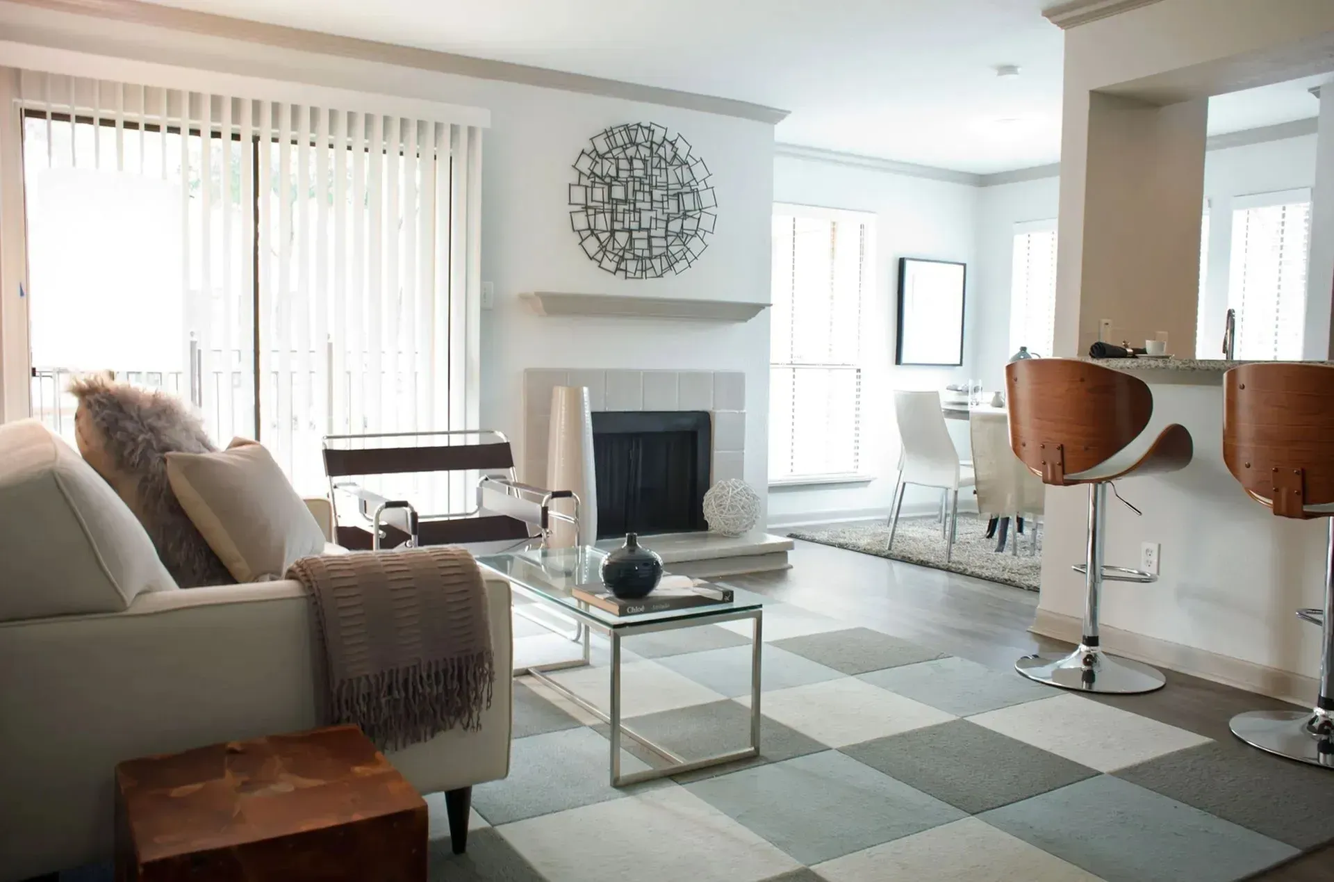Living room with fireplace, gray checkered floor, white couch, and kitchen bar with stools.