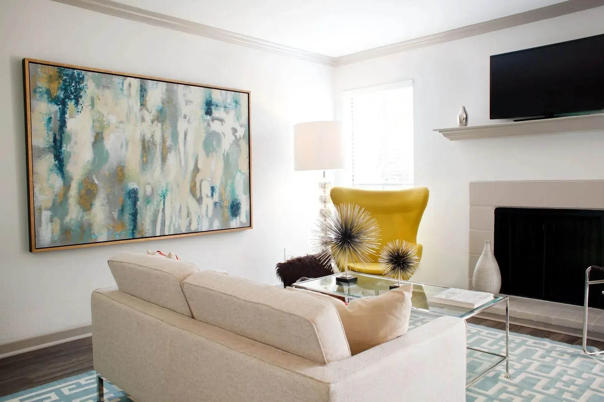 Living room with white walls, a sofa, art, a yellow chair, and a fireplace.