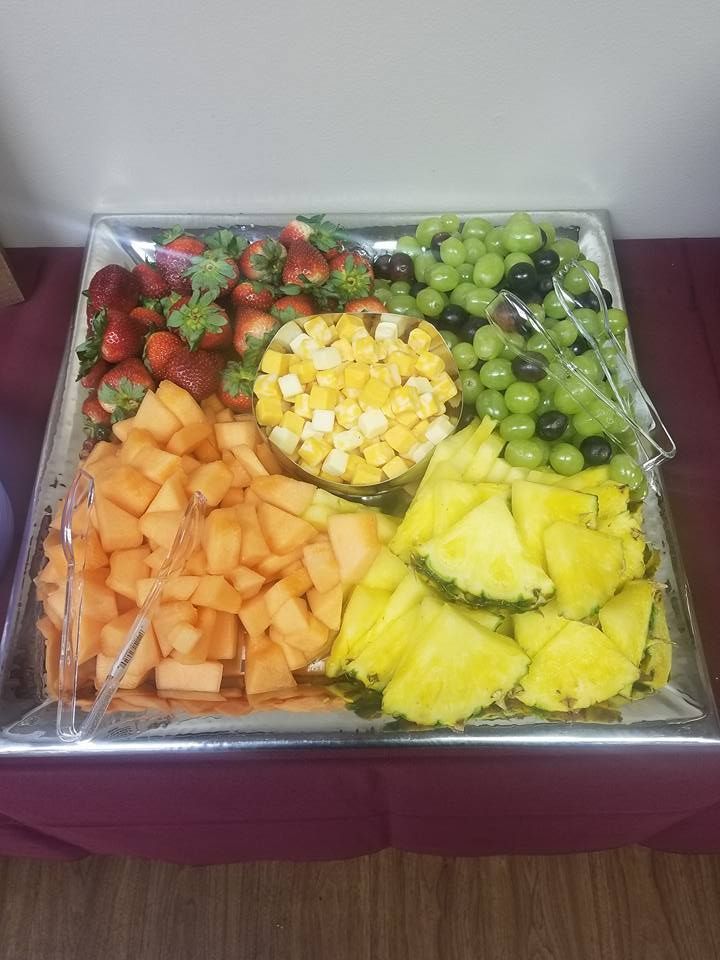 Assorted fruit tray with strawberries, grapes, pineapple, melon, and diced mango in a clear container